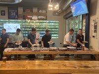 a group of people standing around a table with food